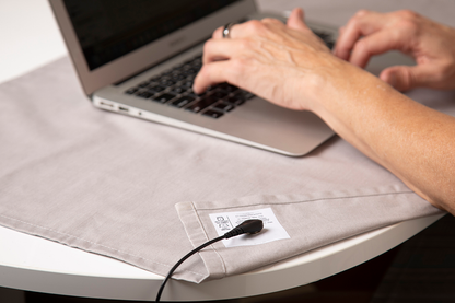 Person types on laptop resting on a gray grounded desk pad. 
